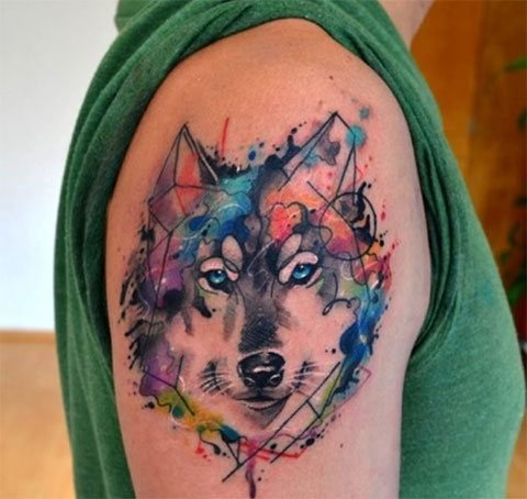 Watercolor tattoo of a wolf on the shoulder