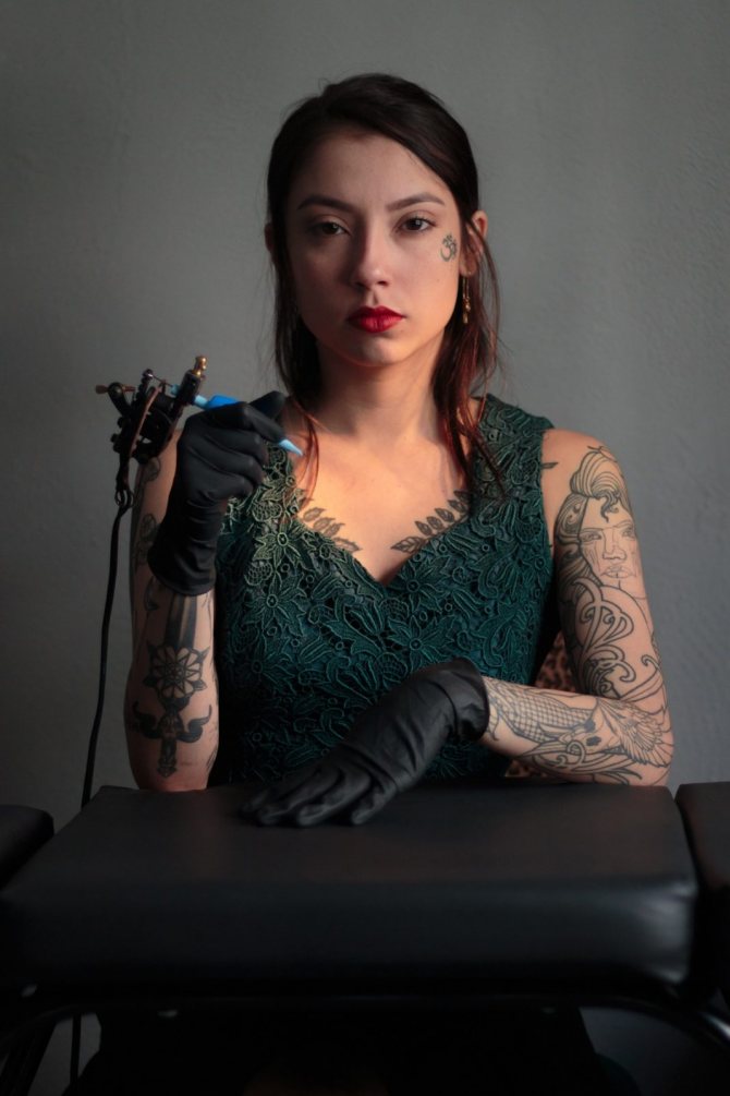 A girl with a tattoo machine in her arms