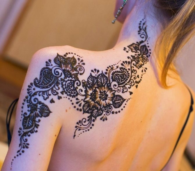 Elegant tattoo in the form of flowers, which affects the shoulder, shoulder blade, neck