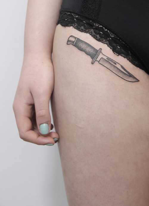 Piccolo tatuaggio a forma di coltello su una ragazza