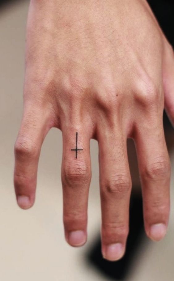 Tattoo of a cross on a finger