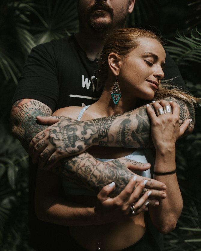 Man with tattoos on arms hugs woman