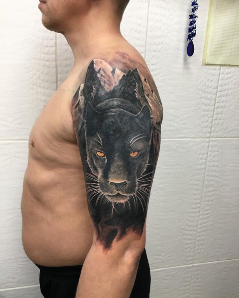 Male tattoo of a panther and mountains on his shoulder