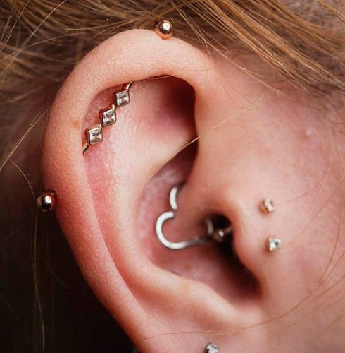 Cartilagine forata nell'orecchio di una ragazza con anello per orecchio, chiodo, catena
