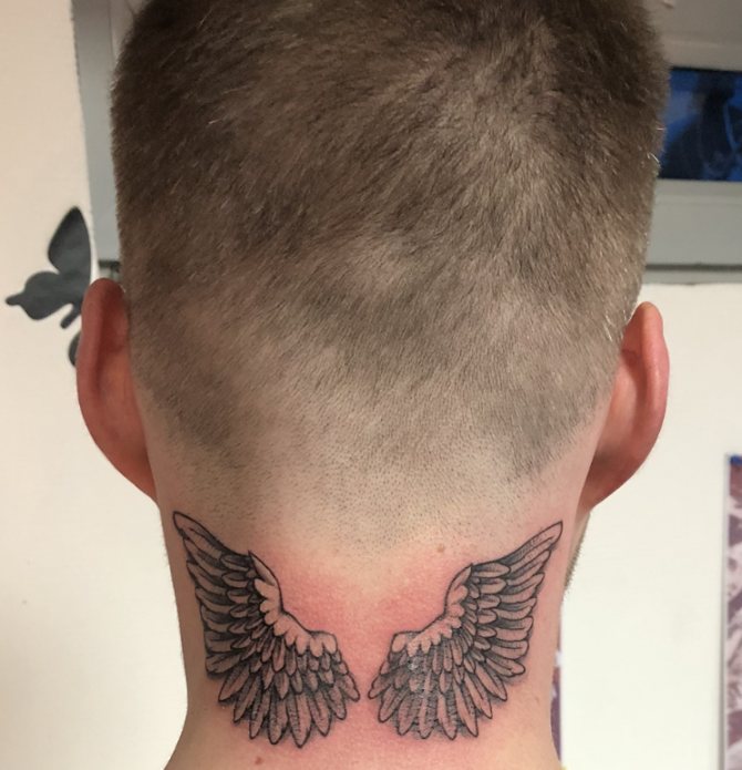 This is how a tattoo of wings looks like on the back of a man's neck