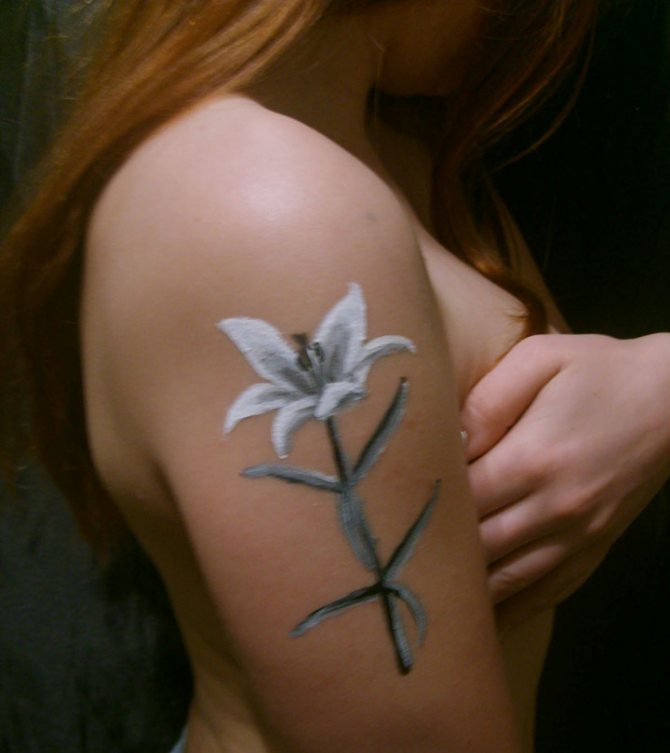 Tattoo of a lily flower on a woman's shoulder
