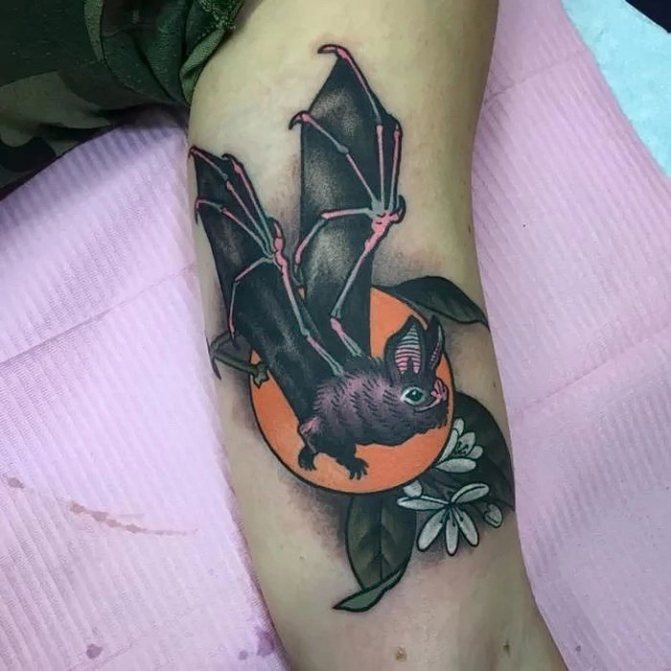 bat tattoo with flowers on his biceps