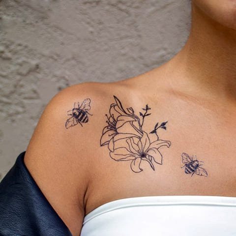 Tattoo on collarbone with bee and flower