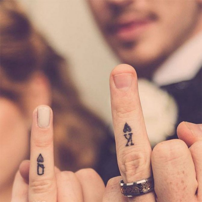 Tattoo on fingers in the form of King and Queen of Cards