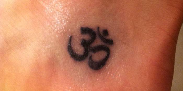 Tattoo on a girl's ankle - the symbol for Om