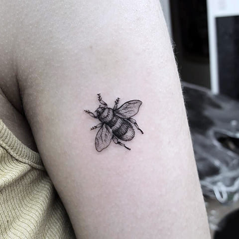 Tattoo of a bee on his shoulder