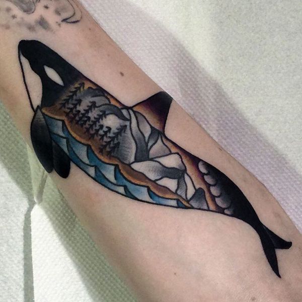 Tattoo in the form of a picture with a dolphin and the nature on his background