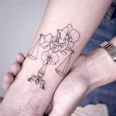 Tattoo of a Libra in combination with flowers
