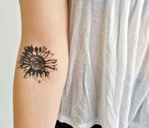 Tattoo on the arm of a girl with a daisy