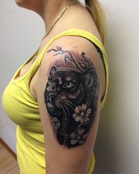 Tattoo of a cougar with flowers on a woman's shoulder