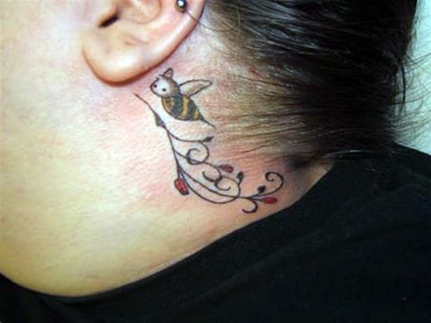 Tattoo of a bee behind the ear