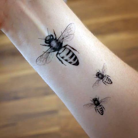 Tattoo of a bee on his arm