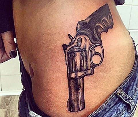 Tattoo of a gun on the side of a girl