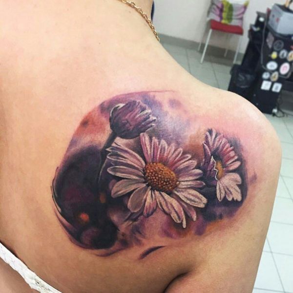 Tattoo of three daisies in the style of realism on the shoulder blade of a girl
