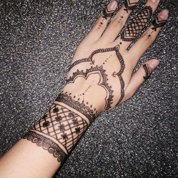 Tattooing mehendi pattern with marker pen on hand