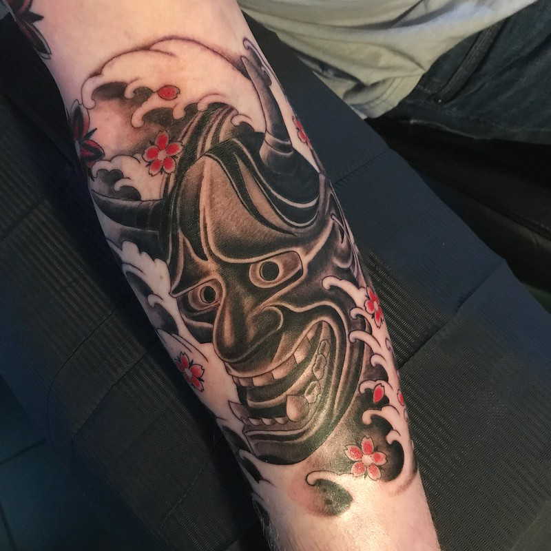 Wave and demon tattoo on forearm