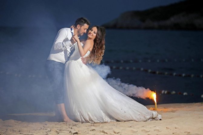The bride and groom dance on the beach at night
